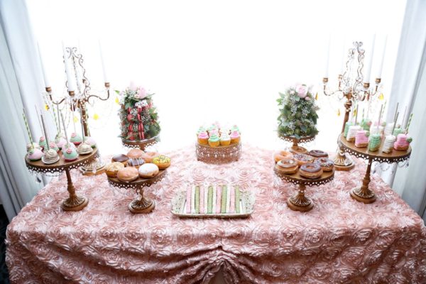A Quinceanera table adorned with a tablecloth and an array of cupcakes and cakes