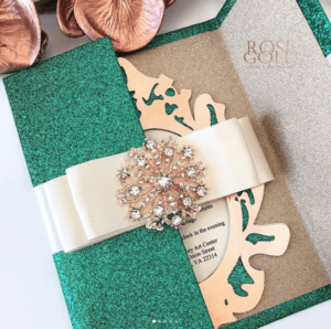 A close up of an emerald green Quinceanera invitation on a table