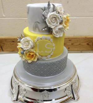 A three-tiered yellow Quinceanera cake with flowers on top
