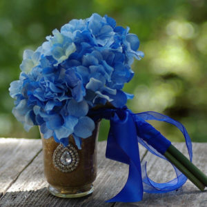 A beautiful floral arrangement for a Quinceanera celebration, featuring cobalt blue flowers in a vase on a table