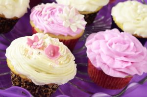 A plate of cupcakes with pink frosting and sprinkles, perfect for a Quinceanera celebration. Learn how to make the delicious Cupcake frosting recipe.