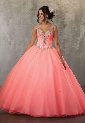 A woman in a pink Quinceanera ball gown standing in front of a wall