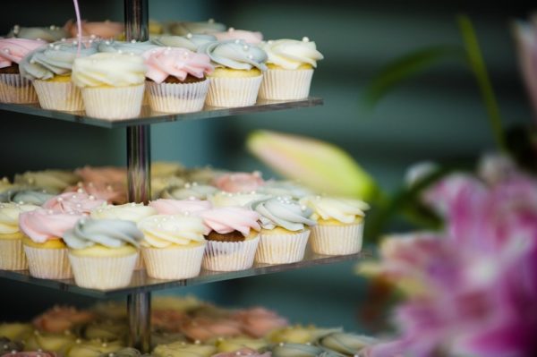 Three-tiered cupcakes with frosting and flowers in the background, perfect for a quinceañera celebration