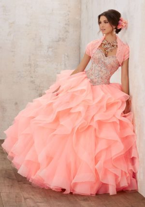 A woman in a pink Quinceañera dress leaning against a wall, showcasing Morilee Quinceanera dresses