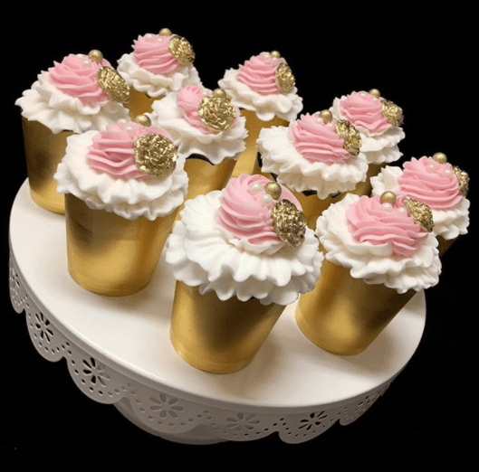 A pink and gold cupcakes on top of a buttercream Quinceanera cake