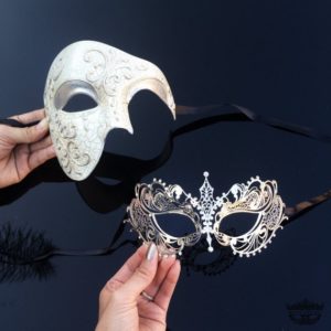 Two romantic masks, one white and one black, being held by a person at a Quinceanera celebration.