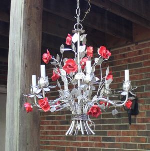 A beautiful chandelier decorated for a Quinceañera, featuring red roses hanging from it.