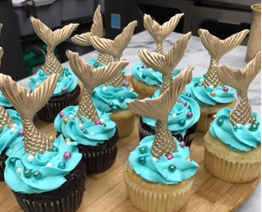 Quinceanera themed cupcake with blue frosting and gold decorations
