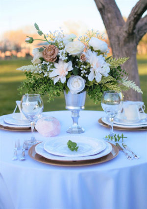 A Quinceanera centrepiece party featuring a white table with a vase of flowers on top