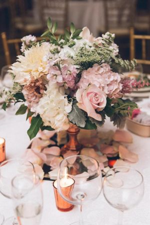 A Quinceanera table with rose gold decorations, including flower arrangements and candles