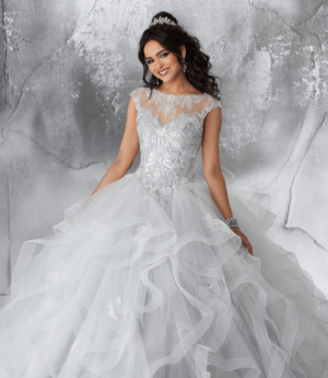 A woman in a silver and white Quinceanera dress posing for a picture