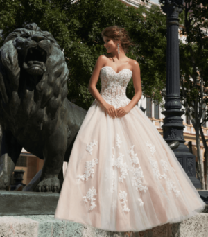 A woman in a Quinceanera gown standing in front of a lion statue
