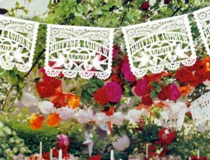 Quinceanera, a table with a bunch of flowers and decorations on it, papel picado