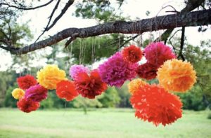 Quinceanera party with colorful tissue pom poms hanging from a tree
