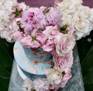 A floral design featuring a bouquet of pink and white flowers in a blue vase, perfect for a Quinceanera celebration.