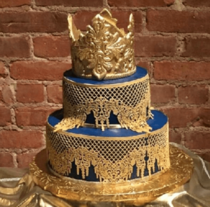 A Quinceanera buttercream cake featuring a blue and gold design with a crown on top.