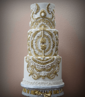 A white and gold Quinceanera cake on a table, with wedding ceremony supplies