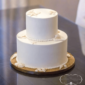 A three-tiered white Quinceanera cake on a table