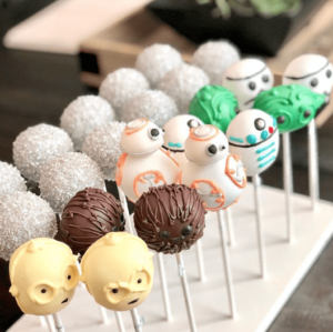 A bunch of cake pops with faces on them and petit four Quinceañera