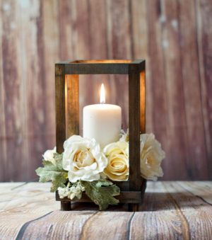 A Quinceanera candle holder centerpiece on a wooden table, with a lit candle