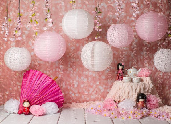 Quinceanera, a pink backdrop with white paper lanterns, a pink fan, and a Japanese themed party