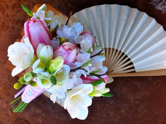 Floral design with a bouquet of flowers and a fan on a table for a Quinceanera celebration.
