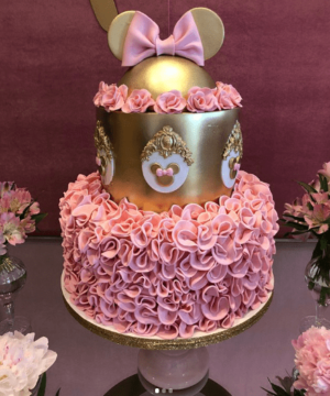A pink and gold Quinceanera cake decorated with a Minnie Mouse topper
