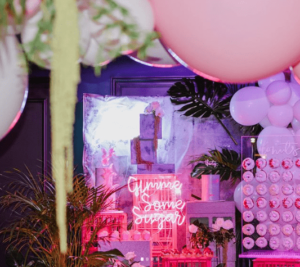 A Quinceanera themed image featuring a lilac floral design and a bunch of balloons in a room.