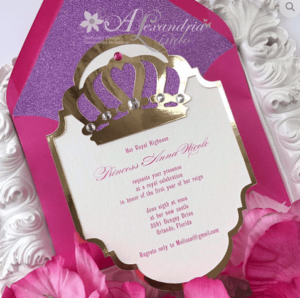 A Quinceanera invitation with a pink and purple design featuring a crown on it