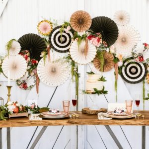 A table topped with lots of different types of paper fans at a Quinceanera party