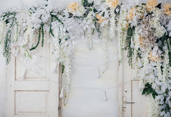 A Quinceanera celebration with a beautiful display of white flowers hanging from a wall