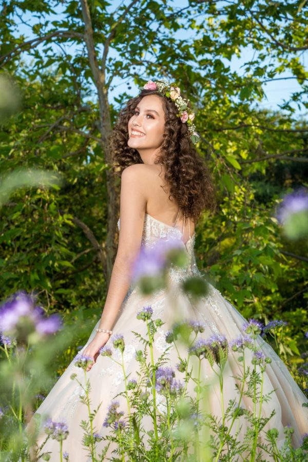 A woman in a Quinceanera dress standing in a flower garden