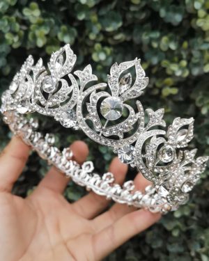 A hand holding a Mexican Quinceanera crown jewellery tiara with diamonds on it