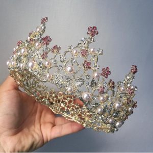 Quinceanera jewellery, a hand holding a crown with pearls and crystals.
