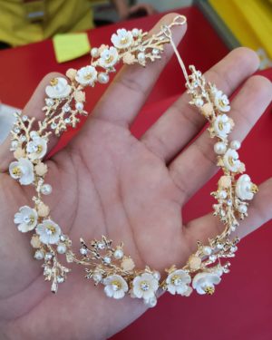 A hand holding a gold and white bracelet with a pearl necklace