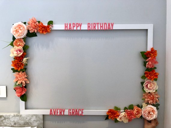 A person holding a picture frame with floral design and flowers on it