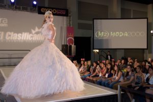 A woman in a Quinceanera gown walking on a runway at a fashion show