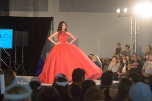 Quinceanera fashion show: Haute couture, a woman in a red dress walking down a runway.