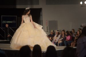 A woman in a Quinceanera gown walking down a runway