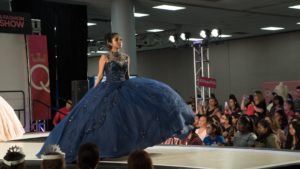 Quinceanera fashion show, a woman in a blue dress walking down a runway