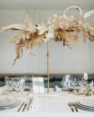 Dried flower arrangements for a Quinceanera wedding centerpiece, a table set with Quinceanera themed plates and silverware.