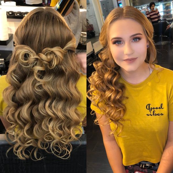 A woman with long curly blond hair in a salon, getting a Quinceanera hairstyle
