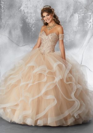 A woman in a champagne Quinceanera dress posing for a picture