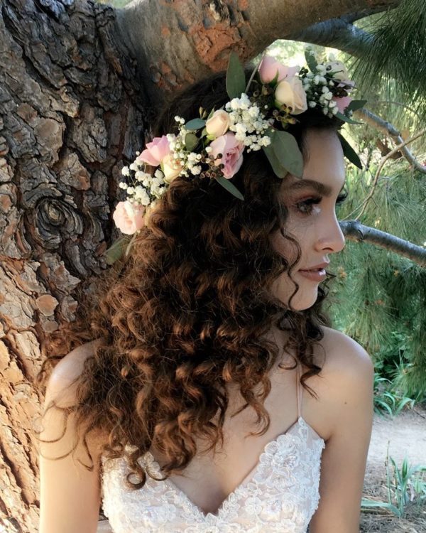 A woman with a flower crown on her head, showcasing a Quinceanera hairstyle