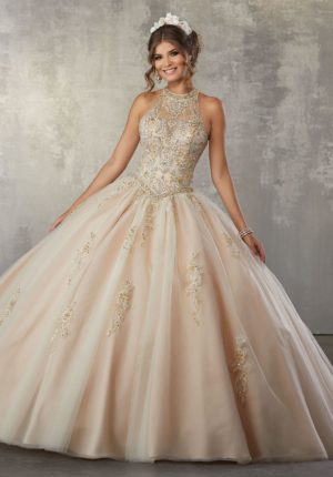 A woman in a champagne Quinceanera dress posing for the camera in a ball gown