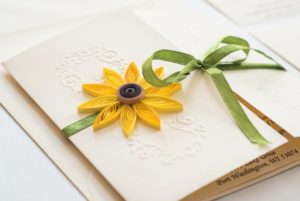 A close up of a paper floral design on a book with a flower on it, depicting a Quinceanera theme.