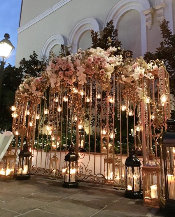 An entrance to a Quinceanera event featuring a beautifully decorated arch with candles and flowers.