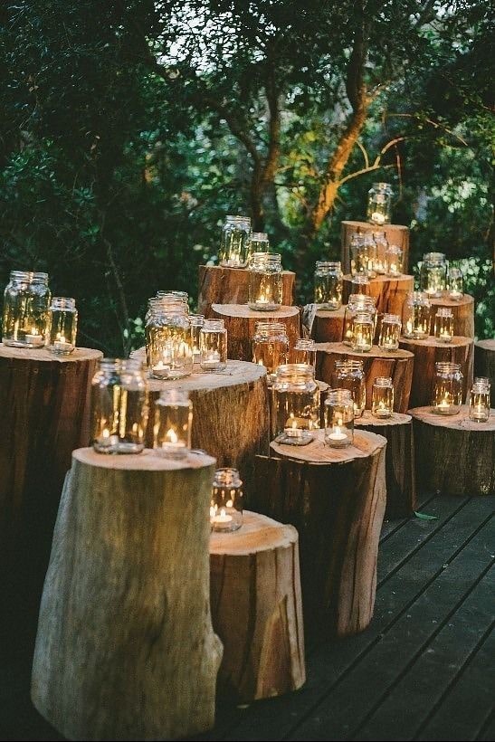 Quinceanera, a forest-themed table decor with a wooden table adorned with candles next to a tree stump