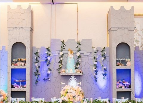 A table elegantly decorated with flowers and a Quinceanera cake set in a beautiful Majorelle Blue theme.