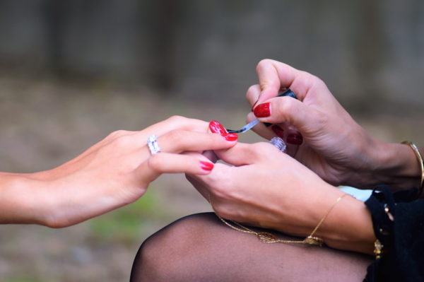Woman receives a red manicure by nail technician